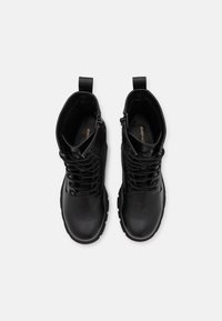 Bottines noires à lacets avec une tige en cuir lisse, bout arrondi, semelle en caoutchouc texturée et languettes sur le col pour un enfilage facile.