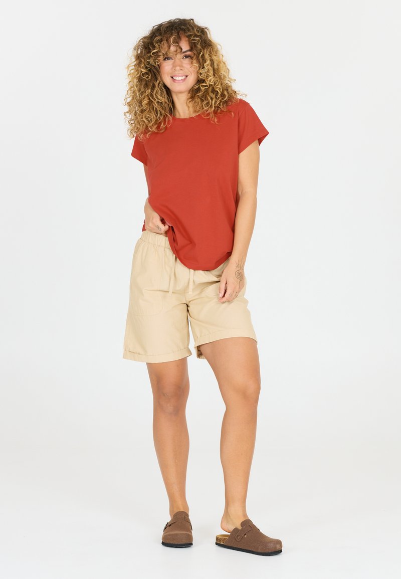 Rød T-shirt med korte ærmer, beige elastik-liv shorts med lommer og brune klipklapper. Simpelt design, afslappet pasform, blød tekstur.