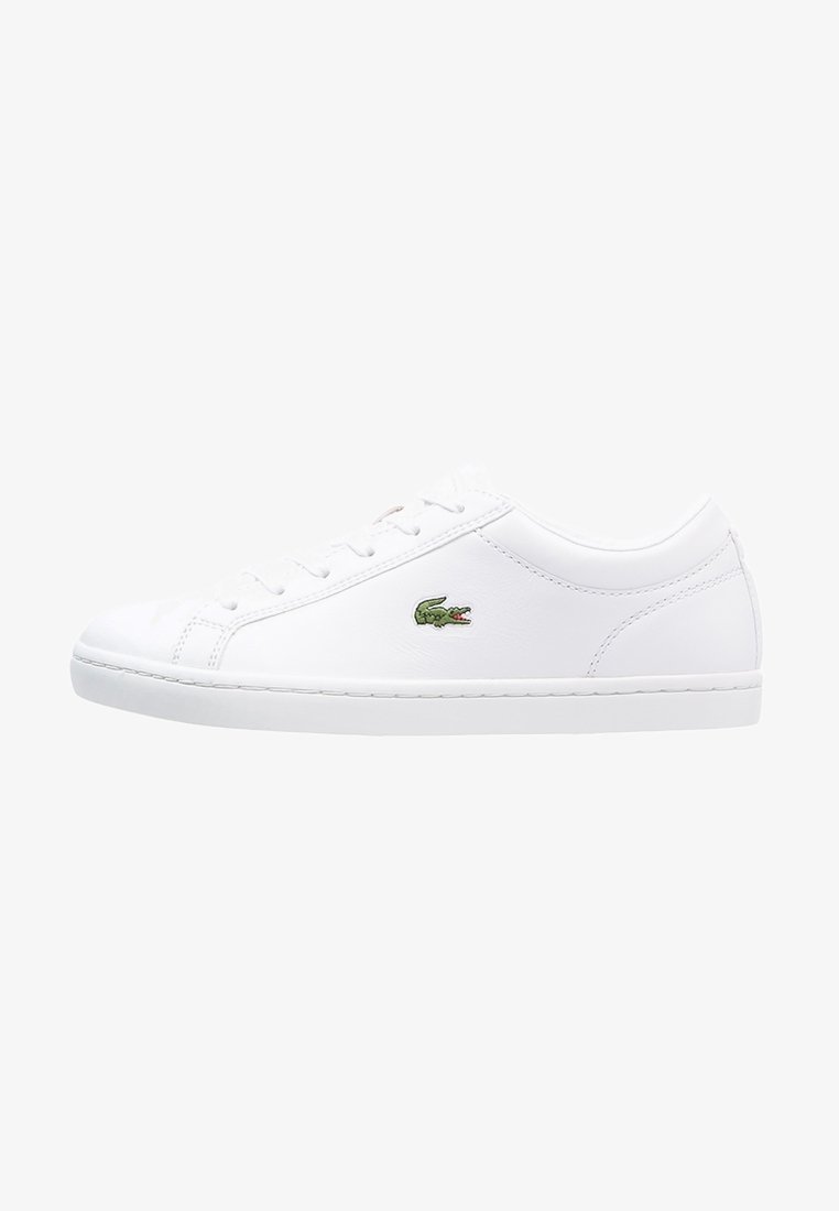Baskets basses en cuir blanc avec fermeture à lacets et logo crocodile vert sur le côté, semelle blanche plate et coutures minimales.