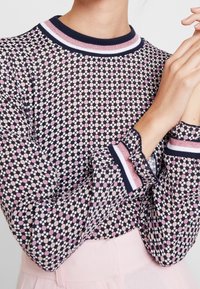 Langarmshirt in een marineblauwe basis met multicolore stippen. Bevat gestreepte kraag en mouwen in roze en marineblauw. Getextureerde, doorzichtige stof.