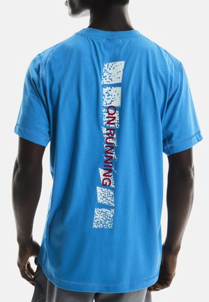 Blaues T-Shirt mit kurzen Ärmeln aus weicher Baumwolle. Hat einen abstrakten weißen und roten Grafikdruck auf dem Rücken und einen runden Halsausschnitt.