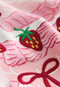 Pamučna tkanina s ružičastom pozadinom i izvezenim jagodama, žutim sjemenkama i zelenim listovima, uz ružičaste mašne i kovrče.