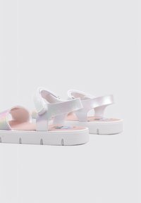 Sandalias blancas con un acabado brillante e iridiscente, que cuentan con correas ajustables, diseño abierto y una plantilla acolchada rosa.