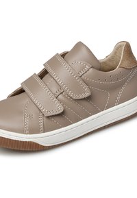 Chaussure en cuir beige avec deux bandes velcro, semelle en caoutchouc blanche et accents marron. Présente des détails cousus et un design perforé sur le côté.