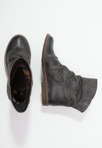 Bottines en cuir noir avec un bout arrondi, un design souple et un petit talon en caoutchouc marron. L'intérieur présente une doublure rayée multicolore.