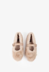 Scarpe slip-on beige pelose con punta arrotondata, caratterizzate da una texture in pelliccia sintetica e una fascia stretta con una fibbia metallica a metà piede.