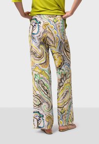 Pantalons à motifs floraux dans des tons pastel avec des accents jaunes, verts et bruns. Design évasé, tissu léger et taille élastique.
