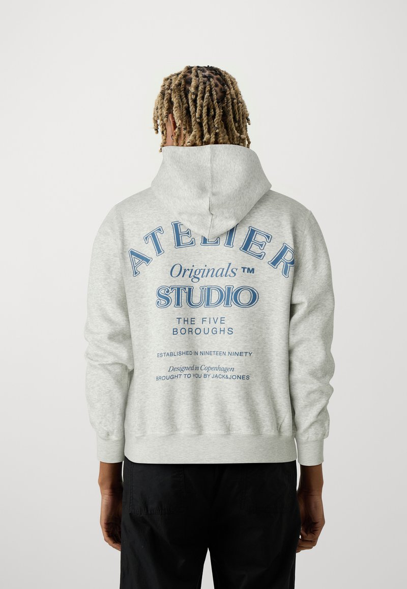 Sweat-shirt gris avec capuche, comportant du texte bleu au dos : "ATELIER Originals STUDIO THE FIVE BOROUGHS." Texture douce, coupe standard.