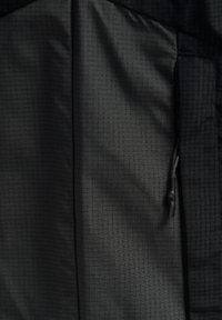 Fodera interna in tessuto nero con un sottile motivo a griglia, dotata di un tassello regolabile sul lato destro e una texture liscia.