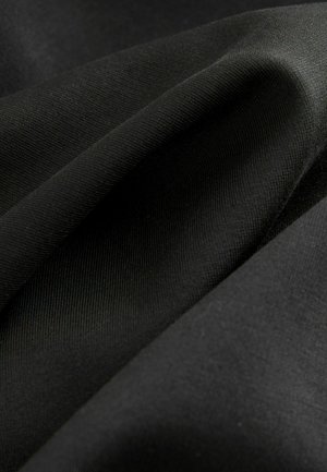 Černá textilie se hladkým, mírně lesklým povrchem. Více vrstev látky uspořádaných, které předvádějí jemný žebrový vzor a měkkost.