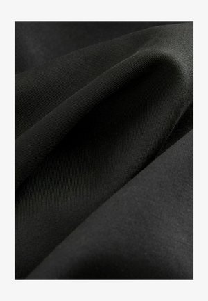 Zwarte stof met een gladde, licht glanzende textuur. Meerdere lagen stof gedrapeerd, met een subtiel ribbelpatroon en zachtheid.