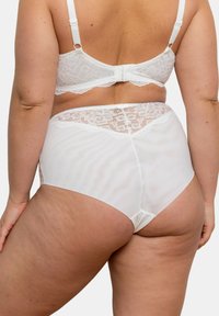 Soutien-gorge blanc avec des bordures en dentelle et culottes taille haute, présentant une texture de tissu transparent, des détails en dentelle florale et des bretelles réglables.