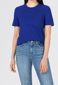 Blå bomullströja med rund halsringning och korta ärmar, tillsammans med ljusblå denim jeans med hög midja och klassisk rak passform.