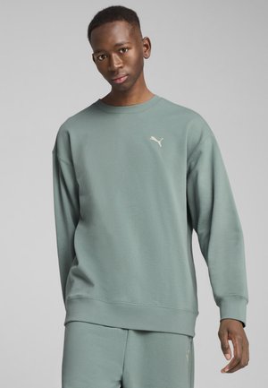 Jasnozielony sweatshirt z długimi rękawami, ściągaczami na mankietach i okrągłym dekoltem. Posiada małe, off-white logo Puma na klatce piersiowej.