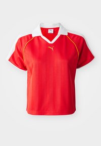 Red sporty polo shirt with white collar and sleeves, featuring vertical stripes and a small gold logo on the front. Lightweight material.