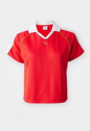 Red sporty polo shirt with white collar and sleeves, featuring vertical stripes and a small gold logo on the front. Lightweight material.