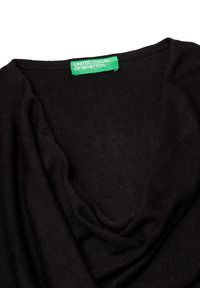 Černý pletený svetr s volným výstřihem, ozdobený zelenou nálepkou s nápisem "UNITED COLORS OF BENETTON." Měkká textura, hladký povrch.