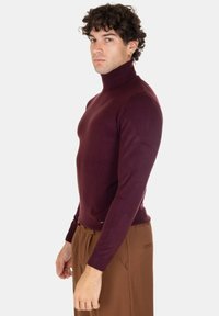 Maglione a collo alto color bordeaux realizzato in un tessuto a maglia liscia, dal design aderente, con maniche lunghe e una finitura pulita all'orlo.