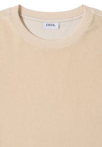 Beżowa prążkowana bawełniana koszulka z okrągłym dekoltem, o gładkiej fakturze i widocznych szwach. Metka z napisem „CECIL” znajduje się przy kołnierzu.