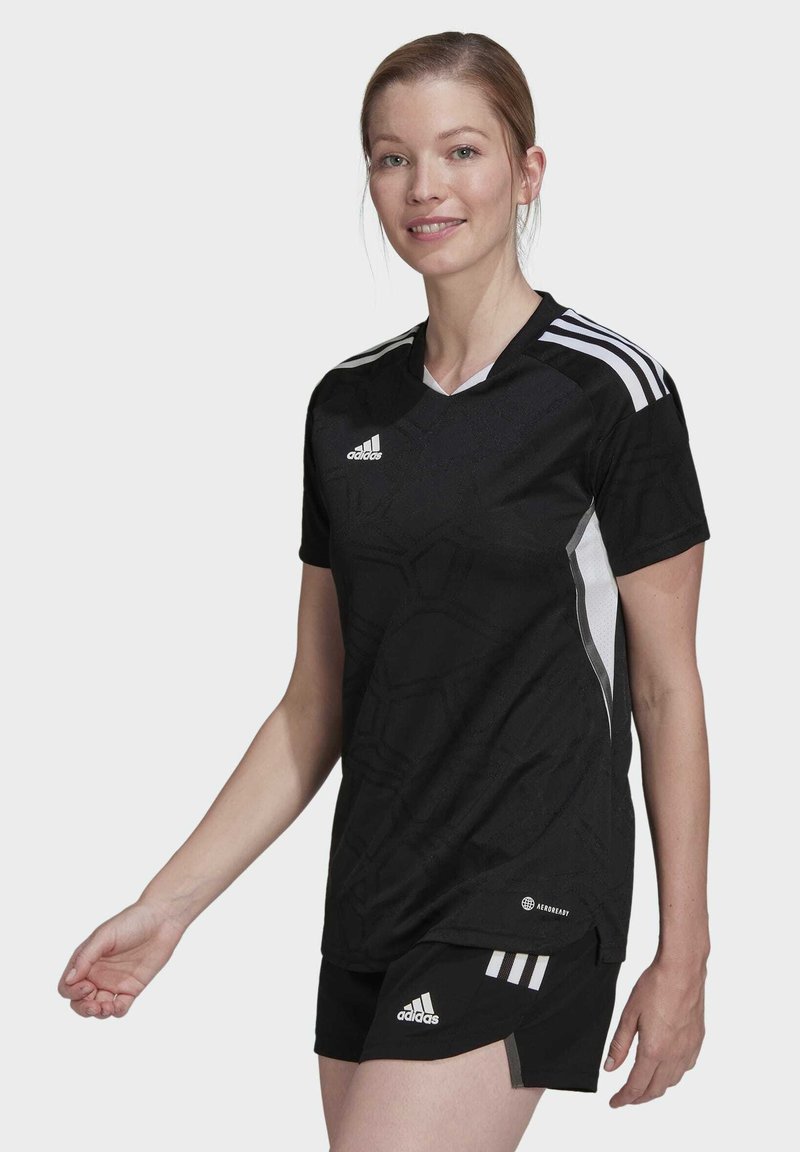 Camiseta de fútbol negra con un patrón texturizado, acentos blancos y tres franjas en los hombros, combinada con pantalones cortos negros que tienen franjas.