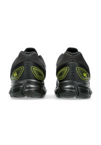 Baskets de course noires avec tige en mesh, talon texturé, amorti en gel et accents jaune vif. Comprend une semelle extérieure sculptée pour une meilleure traction.