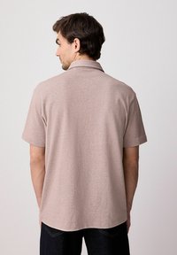 Struktureret lys brun polo t-shirt med klassisk krave og korte ærmer, i en afslappet pasform og med en lige kant.