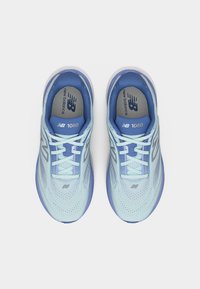 Ζευγάρι ανοιχτό μπλε παπούτσια τρεξίματος New Balance 1080 με λευκά κορδόνια και μαλακό μπλε εσωτερικό, εμφανισμένα από πάνω σε λευκό φόντο.