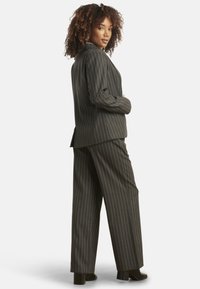 Gray pinstriped suit with a tailored blazer and wide-leg trousers, featuring a smooth texture and a subtle sheen. Stands on a solid background.