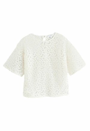 Biała bluzka z krótkim rękawem, z florystycznym wzorem teksturowym i okrągłym dekoltem. Posiada zapięcie na guziki z tyłu i luźny krój.