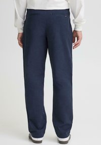 Pamukne mornarsko plave hlače opuštenog kroja, s glatkom teksturom, dva stražnja džepa i suptilnim detaljima šavova.