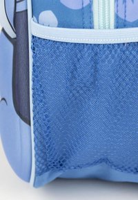 Blauwe rugzak met een mesh zijvak, gladde stof en lichtblauwe ritsaccenten. Textuurmateriaal voor duurzaamheid en flexibiliteit.