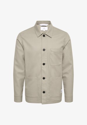 Bežinė striukė su apykaklės dizainu, keturiomis priekine kišenėmis, juodais mygtukais ir etikete kairėje pusėje. Lygi audinio tekstūra.