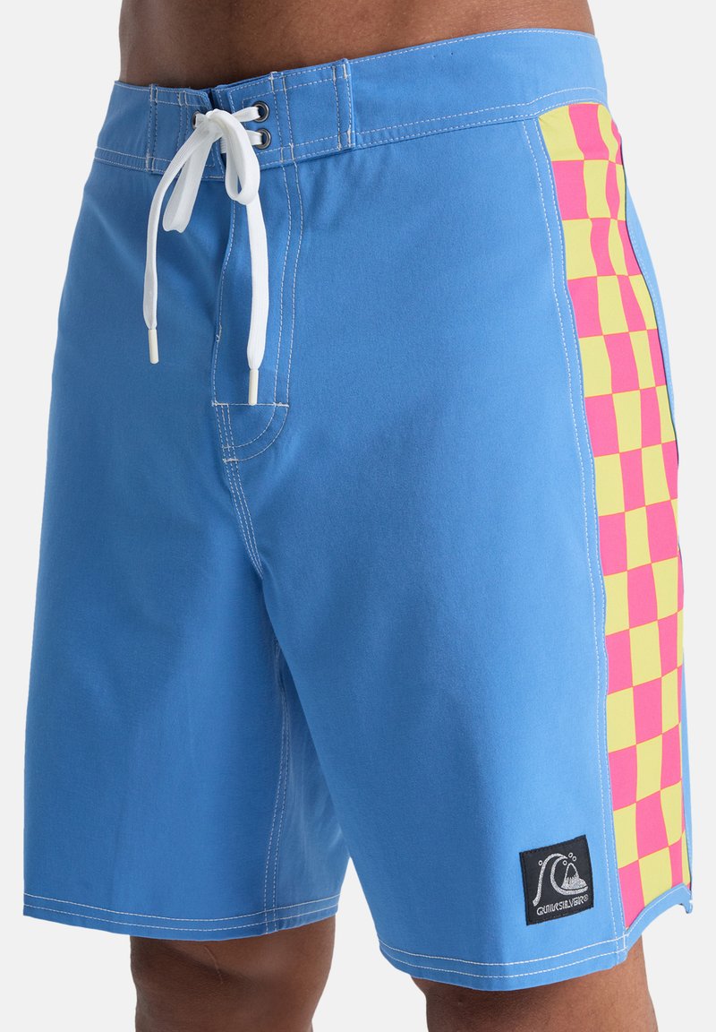 Niebieskie kąpielówki z kontrastującym różowo-żółtym wzorem w kratkę po bokach, wyposażone w biały sznurek i naszywkę z logo.