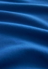 Blauer Baumwollstoff mit glatten, strukturierten Wellen und einem einheitlichen Webmuster, das eine lebendige Farbe und Weichheit zeigt.