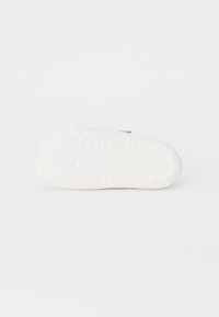 Hvit sneakersåle med teksturert overflate, som har et mønster for grep og en rund tådesign. Logo preget på siden.
