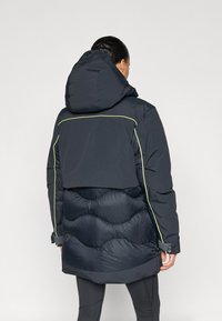 Tumesinine puffer-jakk tekstuurse alumise osaga, kapuutsi ja kontrastse helerohelise äärisega. Omadusteks lühendatud ülakeha disain ja elastsed varrukaservad.