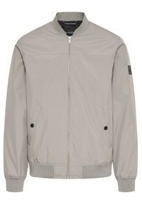 Hellgraue Bomberjacke mit gerippten Bündchen und Saum, ausgestattet mit einem Reißverschluss vorne, zwei seitlichen Taschen und einem Stoffpatch am Ärmel.