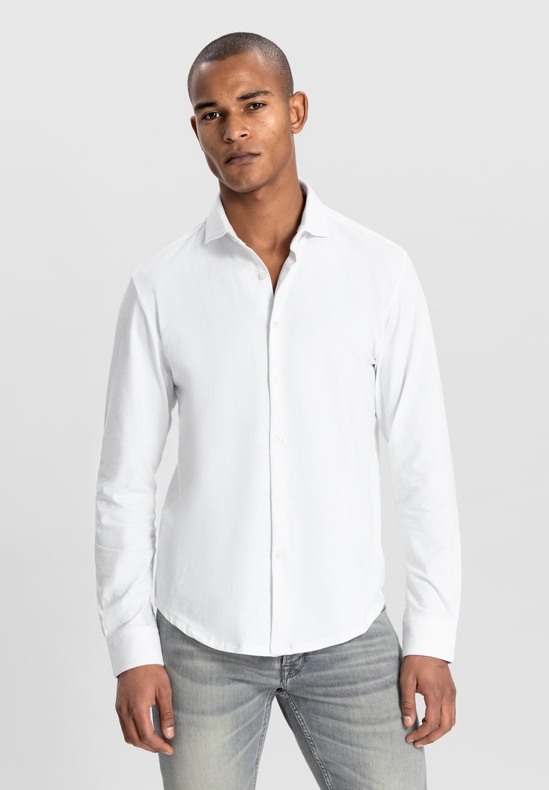 Witte lange mouwen button-up shirt van katoen. Heeft een klassieke kraag en een rechte snit, gecombineerd met lichte spijkerbroek.