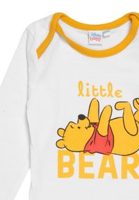 Body bianco a maniche lunghe con un'illustrazione di un orso cartone sdraiato di colore giallo con una maglietta rossa, e la scritta "little BEAR" in arancione.