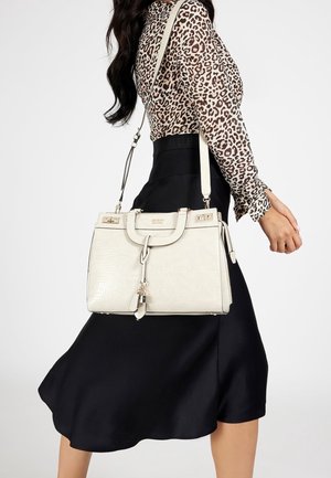 Sac en cuir blanc avec finition texturée, quincaillerie dorée, poignées supérieures et une bandoulière amovible, associé à une jupes satin noir.