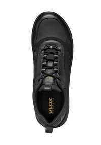 Sneaker nera in tessuto e pelle con forma arrotondata, chiusura con lacci elastici e logo dorato all'interno. Dettagli di superfici lisce e testurizzate.