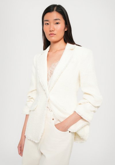 Witte textuur blazer met rafelige randen, een getailleerde pasvorm en een enkele knoopsluiting, gecombineerd met lichtgekleurde broek.