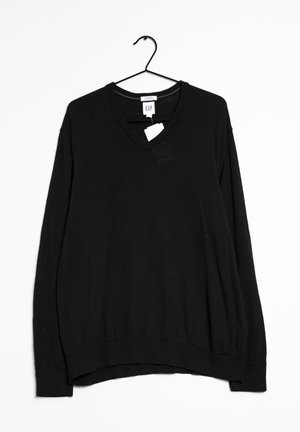 Pull noir à manches longues avec col en V suspendu à un cintre noir avec une étiquette de la marque GAP blanche visible sur le col.