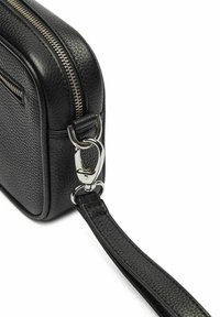 Svart läder crossbody-väska med en texturerad yta, silverdragkedja och metallspänne. Har en avtagbar rem för mångsidighet.