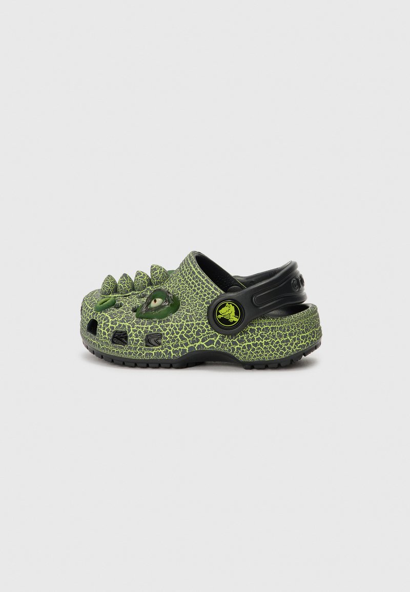Green patterned clogs with a cracked texture and black accents, featuring a spiked front, cutouts, and a back strap for secure fit.