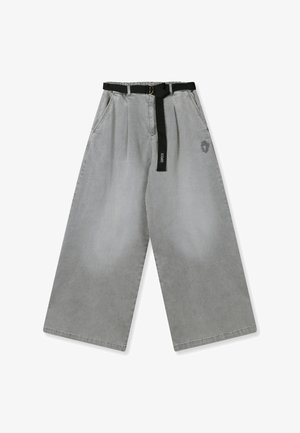 Pantalones anchos de mezclilla gris con un cinturón negro con una hebilla circular y un pequeño logo bordado en el lado izquierdo delantero.