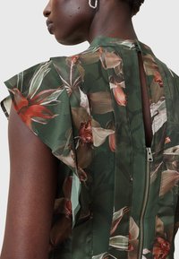 Floral patterned dress with green fabric, featuring ruffled sleeves, back zipper closure, and pleated design elements.