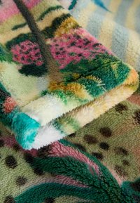 Pătură din fleece cu culori vibrante precum verde, roz și turcoaz; material texturat, pufos, cu modele florale și abstracte.