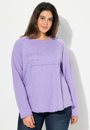 Camicia viola a maniche lunghe con scollo rotondo, che presenta una definizione stampata di "sorriso" sulla parte anteriore. Tessuto leggero e morbido.