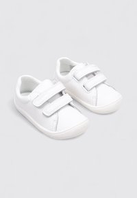 Chaussures blanches pour enfants en matériau synthétique lisse, avec un bout rond, deux sangles Velcro et une semelle en caoutchouc flexible.